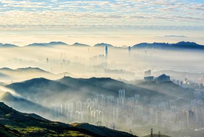 City skyscrapers surrounded by mountains with fog