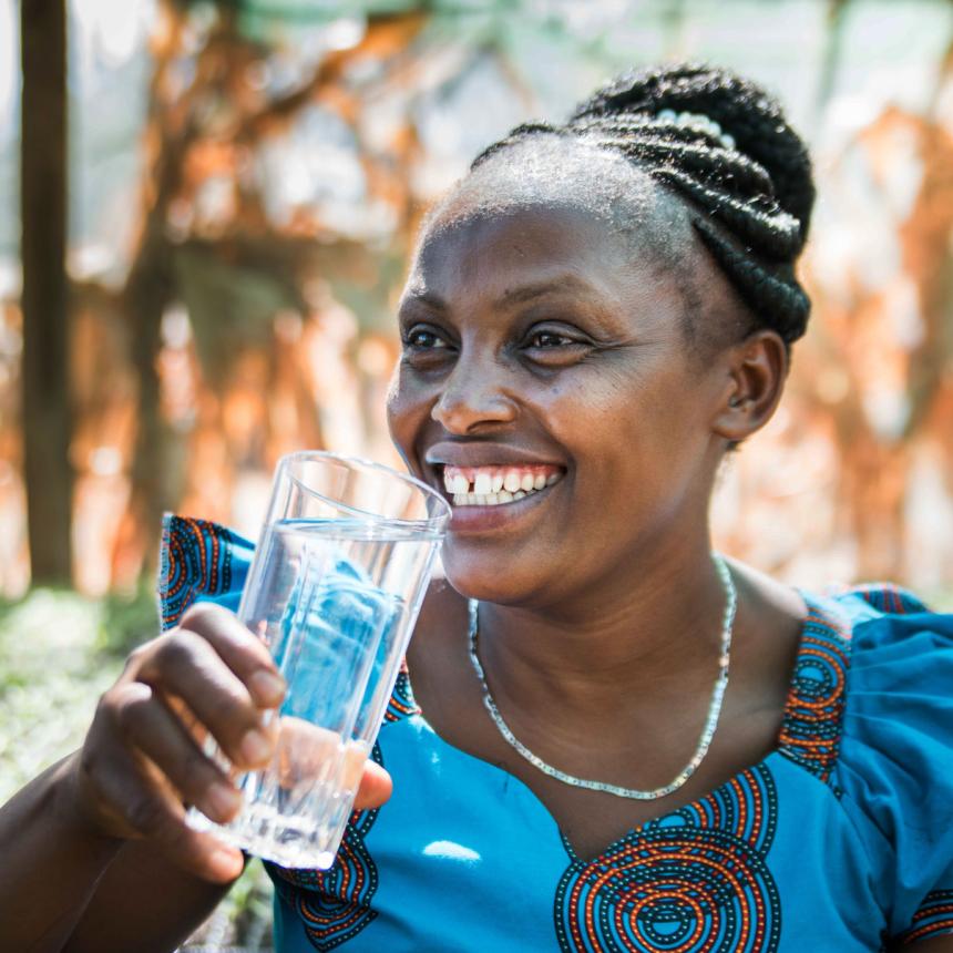 smiling African woman drinking a grass of water