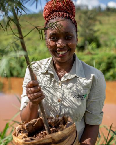 Photo of Florence Mugi holding a new tree seedling for planting