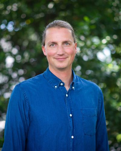 Justus in a blue shirt in front of a green background