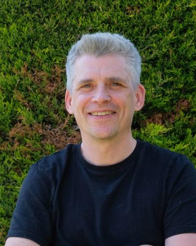 Rob in a black shirt in front of a green background